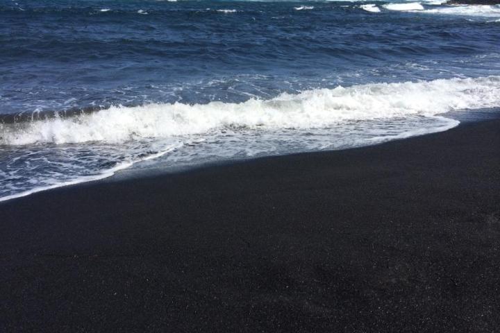 a man walking across a beach next to the ocean